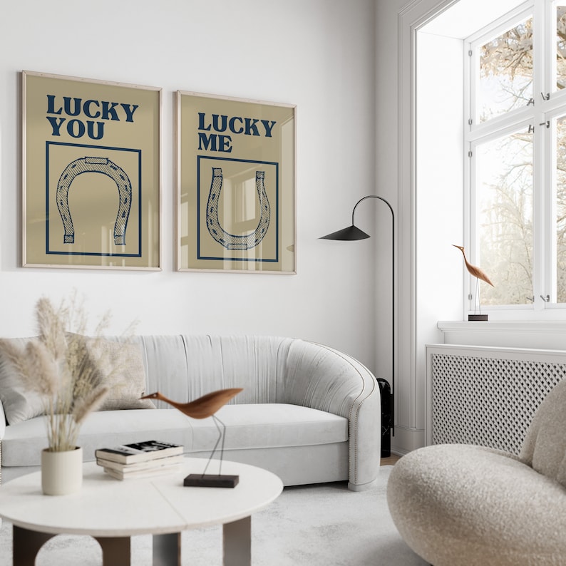 Puede incluir: Dos impresiones enmarcadas con fondo beige y texto azul. El texto de la impresi&oacute;n de la izquierda dice "Lucky You" y el texto de la impresi&oacute;n de la derecha dice "Lucky Me". Ambas impresiones presentan un gr&aacute;fico de herradura azul.