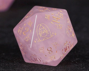 Könnte beinhalten: Ein rosa, rosafarbener Quarz-D20-Würfel mit goldfarbener Metallic-Tinte. Der Würfel hat eine Katzenillustration und die Zahlen 2, 8, 10, 12, 14 und 16.