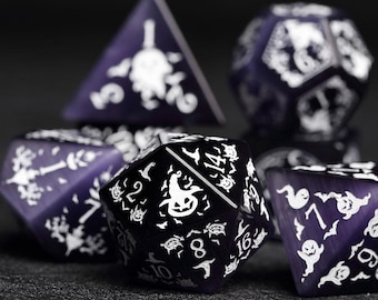 May include: A set of six purple and black dice with white Halloween-themed designs. The dice feature bats, ghosts, pumpkins, and other spooky imagery. The dice are made of a translucent material, and the designs are visible through the dice.