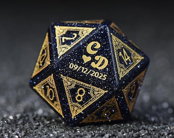 May include: A dark blue, multi-sided die with gold-colored numbers and decorative accents. The die features the initials "C & D" with a heart symbol and the date "09/12/2025" in gold lettering. The die has a glittery appearance.