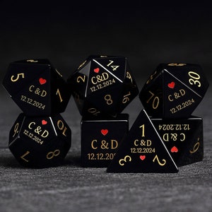 May include: Set of six black dice with gold numbers and a red heart. Each die has the text "C&D 12.12.2024" on one side.