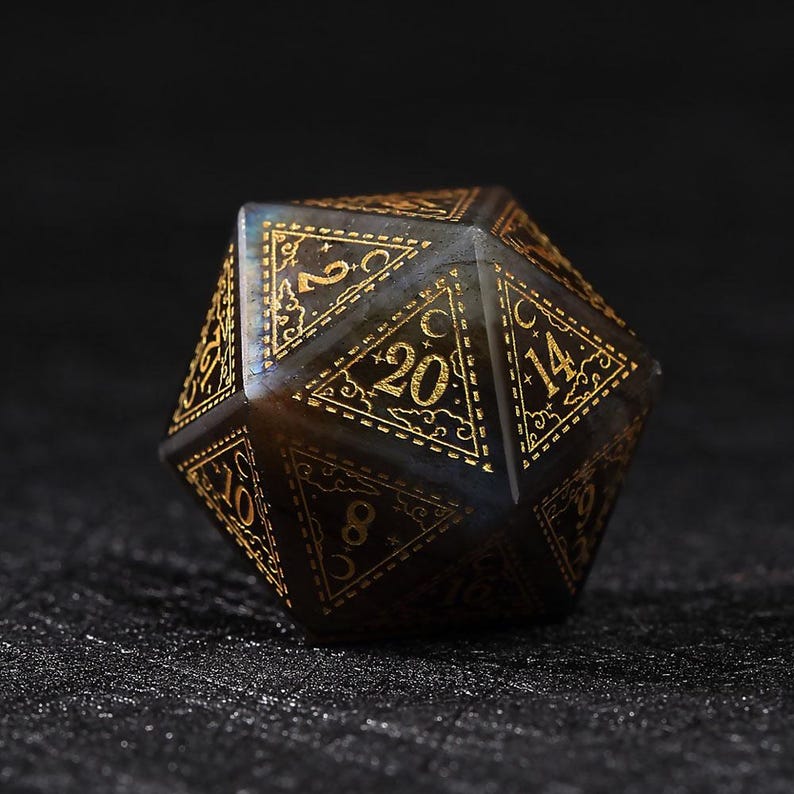 May include: A multi-sided, dark-colored die with gold-colored numbers and decorative accents. The die is a twenty-sided shape, with each side displaying a number from 1 to 20. The die is set against a dark background.