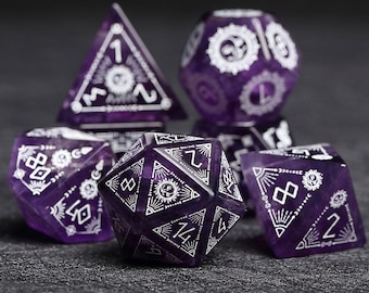 Pode incluir: Conjunto de seis dados de pedra preciosa roxa com desenhos e números gravados em branco. Os dados têm várias formas, incluindo uma pirâmide, uma esfera e um dado de 20 lados. Para jogos de tabuleiro.