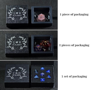 May include: Black boxes with engraved initials and dates, containing dice sets. One box holds a single pink die, another has two dice, and the last contains a set of blue dice. Text on the boxes reads "L K 11.11.2024" and "C & D 12.12.2024".