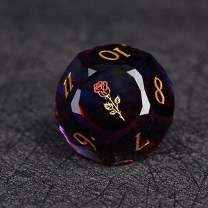 Op de afbeelding: Een veelzijdige D20 dobbelsteen in donkerpaars en blauw met gouden cijfers en een gouden rozenembleem. De dobbelsteen is ontworpen voor tabletop-rollenspellen en heeft een gepolijst, reflecterend oppervlak.