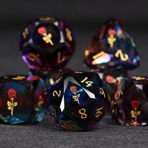 Op de afbeelding: Set iriserende polyhedrale dobbelstenen met gouden cijfers en een rood rozenontwerp. De dobbelstenen, waaronder d20, d12 en d6, zijn gemaakt van een donker, doorschijnend materiaal met een glinsterend effect.