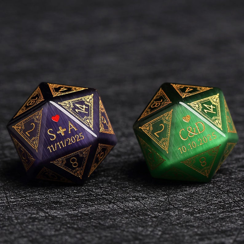May include: Two dodecahedron dice, one purple and one green, with gold-colored filigree and engraved text. The purple die has "S+A" and "11/11/2025". The green die has "C&D" and "10.10.2025".