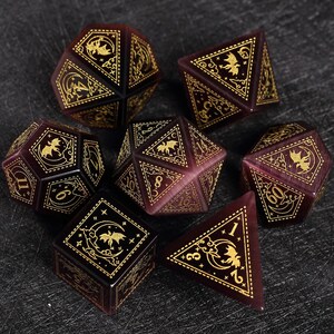 May include: A set of seven burgundy polyhedral dice with gold detailing. Each die features a bat and moon design, alongside numbers. These dice are designed for tabletop role-playing games.