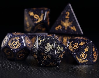 Pode incluir: Um conjunto de seis dados pretos e dourados com acabamento brilhante. Os dados são numerados 12, 2, 14, 8, 6 e 30. Cada dado tem um design único com um dragão, um morcego e outros símbolos.