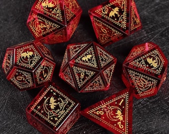 Op de afbeelding: Set van zeven rode en gouden polyhedrale dobbelstenen voor tabletop games. Elke dobbelsteen heeft gouden illustraties van vleermuizen en manen, met gouden cijfers. De dobbelstenen liggen op een donkere ondergrond.