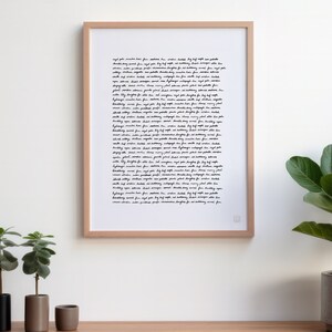 May include: A framed print with a white background and black handwritten text. The text is a long paragraph of cursive writing. The frame is light brown wood.
