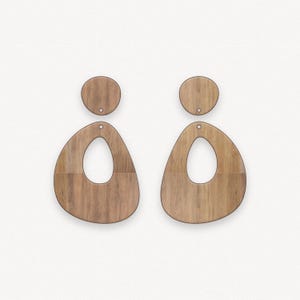 May include: A pair of wooden earrings with a teardrop shape and a smaller circle on top. The earrings have a wood grain pattern and a hole in the center for hanging.