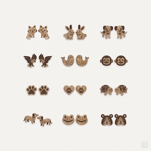 Pode incluir: Conjunto de 10 pares de brincos de madeira com vários desenhos de animais e natureza. Os desenhos incluem gatos, coelhos, cães, pássaros, focas, macacos, pegadas, corações, tartarugas, sapos e hamsters.