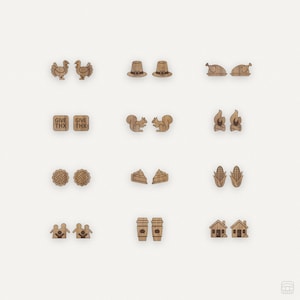 May include: A set of 10 pairs of wooden earrings featuring various Thanksgiving-themed designs, including turkeys, pilgrims hats, squirrels, corn, pie, and houses. The earrings are all made of natural wood and have a rustic, handmade look.