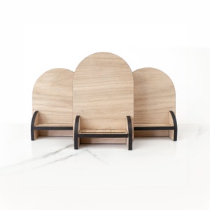 May include: Three wooden display stands with rounded tops and black trim. Each stand has a small shelf.