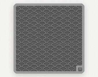 Puede incluir: Un azulejo cuadrado gris con un patrón repetitivo de semicírculos negros y blancos superpuestos. El azulejo tiene un borde ligeramente elevado.