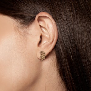 May include: A pair of gold-toned earrings featuring a delicate rose design.