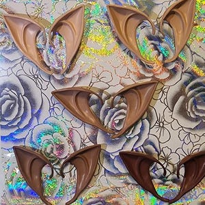 May include: Six pairs of brown elf ears made of flexible plastic. The ears are designed to be worn on the head and are a popular costume accessory.
