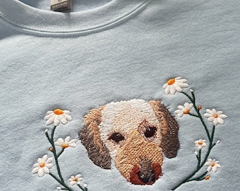 May include: A light blue sweatshirt with an embroidered design of a dog's face surrounded by white daisies.