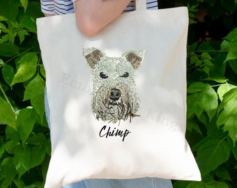 Può includere: Una borsa tote in tela bianca con un'illustrazione in bianco e nero del muso di un cane. Il nome del cane, "Chimp", è stampato in nero sotto l'illustrazione.