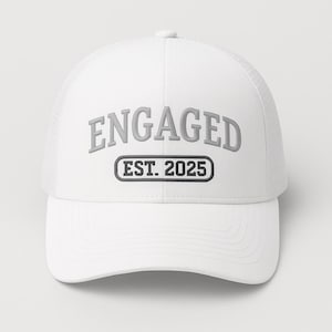Puede incluir: Gorra de camionero blanca con la palabra "ENGAGED" en letras grises. Debajo, dentro de un rectángulo negro, está el texto "EST. 2025". La gorra tiene una parte trasera de malla y una visera curva.