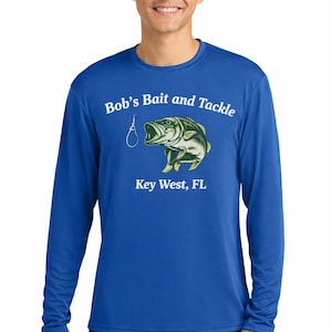Op de afbeelding: Koningsblauw shirt met lange mouwen met de tekst "Bob's Bait and Tackle" en een visafbeelding met een haak. De tekst "Key West, FL" staat eronder.