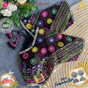 Pode incluir: Top preto bordado com desenhos circulares coloridos e detalhes de espelho. O top apresenta padrões intrincados, lantejoulas e borlas. O texto "The Traditional Street" é visível.
