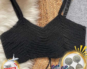 May include: A black beaded top with shoulder straps. The top is covered in small, round beads. The image also includes a gold-rimmed circle with earrings and the text "Get a Surprise Gift". The text "The Traditional Street" is at the top.