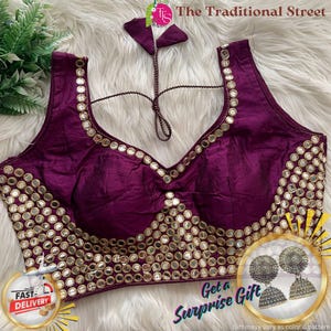 Pode incluir: Uma blusa sem mangas, cor de ameixa, com decote em V profundo. A blusa é adornada com pequenos espelhos redondos ao longo do decote e do corpete. O texto "The Traditional Street" é visível.