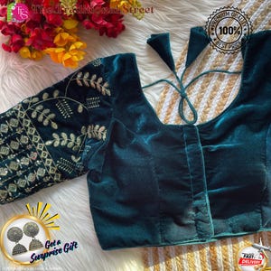 Pode incluir: Uma blusa de veludo verde-azulado com bordados dourados nas mangas. A blusa tem decote redondo e fecho de laço nas costas. O texto "The Traditional Street" está no topo. A imagem também inclui o texto "Get a Surprise Gift", "Premium Quality 100% Best Price" e "Fast Delivery".