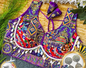 May include: A purple embroidered top with intricate patterns and embellishments. The top features a V-neck design and is adorned with colorful details, including red, orange, and gold accents. The text "The Traditional Street" is visible in the top left corner.