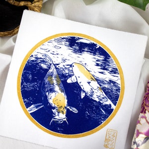May include: A gold and blue print of two koi fish swimming in a circle. The print is on a white background and has a gold border. The artist's signature is in the bottom right corner.