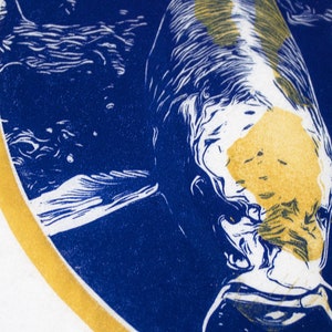 May include: A blue and gold circular print of a fish with white and yellow markings. The fish is swimming in a blue and white background.
