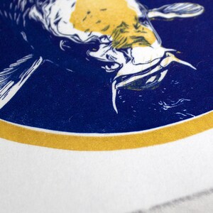 May include: A white and yellow koi fish with blue and white details is printed on a blue background inside a gold circle. The design is on a white fabric.