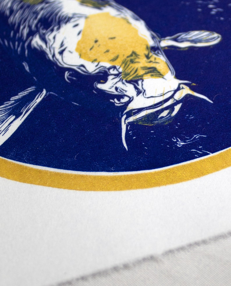 May include: A white and yellow koi fish with blue and white details is printed on a blue background inside a gold circle. The design is on a white fabric.