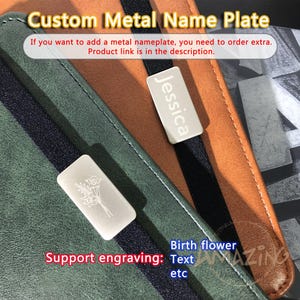 May include: Custom metal name plates with engraved text and birth flower designs. The image shows a green and brown leather notebook with two nameplates, one with the name "Jessica" and the other with a floral design. The text "Support engraving: Text etc" is also visible.