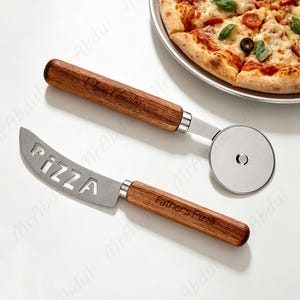 May include: A pizza cutter and a pizza knife. Both have wooden handles and stainless steel blades. The knife blade has the word "PIZZA" cut out. The pizza cutter has a round blade. The knife says "Father's Pizza".