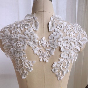 Puede incluir: Aplique de encaje blanco con motivos florales y adornos de perlas. Este delicado encaje es perfecto para añadir un toque de elegancia a los vestidos de novia, los accesorios de novia u otros proyectos de artesanía.