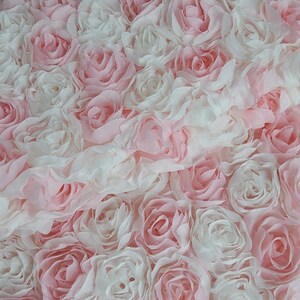 May include: A close-up of a fabric with a pink and white rose pattern. The fabric is made of soft, ruffled material and is perfect for crafting projects.