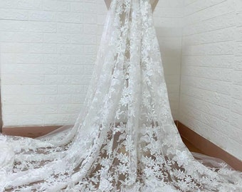 May include: White floral lace fabric with a delicate pattern. The lace is sheer and has a soft, flowing texture.
