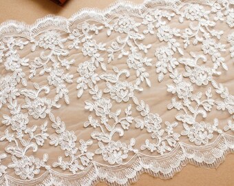 May include: White lace trim with a delicate floral pattern. The lace has a scalloped edge and is perfect for adding a touch of elegance to any project.