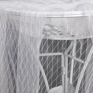 Puede incluir: Red de tul blanca transparente con un patrón de diamante drapeado sobre un marco de metal.