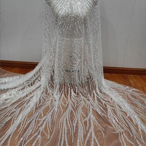 May include: White tulle fabric with silver sequins and beads in a leaf pattern.