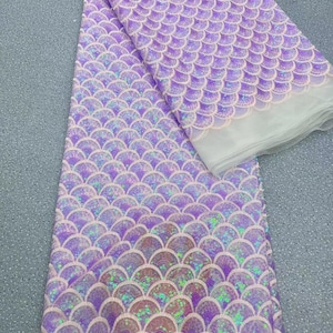May include: Purple iridescent mermaid scale fabric with a sheer mesh backing. The fabric is made of sequins and is perfect for crafting and sewing projects.