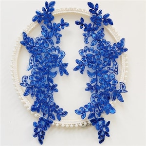 May include: Two blue floral lace appliques with sequins, perfect for adding a touch of elegance to any project.