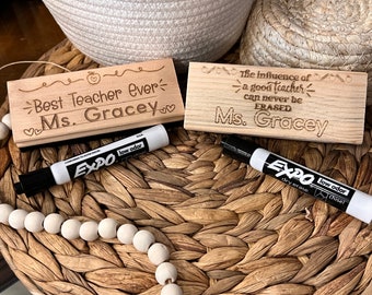 May include: Two rectangular wooden blocks engraved with teacher-themed text and two black Expo low odour chisel tip dry erase markers. The left block reads Best Teacher Ever Ms. Gracey, and the right block reads The influence of a good teacher can never be ERASED Ms. Gracey.