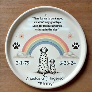 May include: White ceramic plate with a rainbow, two paw prints, and a quote about looking for a loved one in rainbows. The plate also includes the dates "2-1-79" and "6-28-24", the name "Anastasia Ingersoll", and the name "Stacy" in quotes.