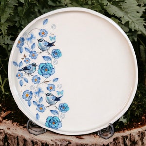 May include: White ceramic serving tray with a blue and white floral design featuring birds. The tray has a raised rim and is perfect for serving snacks or appetizers.