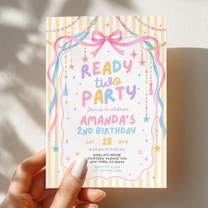 May include: A rectangular birthday invitation card featuring a yellow and white striped background with a pink bow, blue and pink ribbons, and hanging star and bead decorations. The text reads READY TWO PARTY, AMANDA'S 2ND BIRTHDAY, SAT 28 AUG, 2:00 PM TO 4:00 PM, AMELIA'S HOUSE, THIRTEEN AVENUE 33A, NEW YORK, CA 90554, RSVP TO ALMA, 123-456-7890.