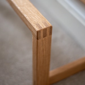 May include: Close-up of a wooden frame with a mitred joint. The wood is light brown and has a natural finish.